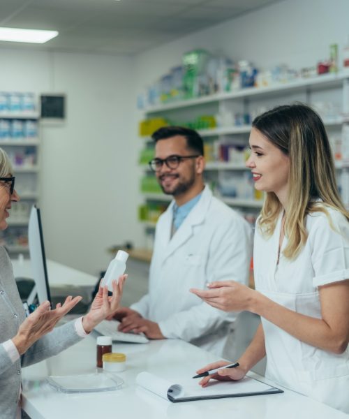 pharmacist-working-on-a-computer-while-female-pharmacist-is-giving-medications-to-senior-patient.jpg